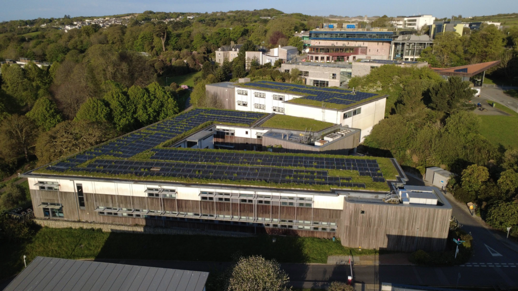 Aerial view of Penryn Campus showing solar panels on the rooftop and surrounding academic buildings.